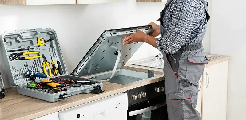 Handyman repairing a cooktop and checking wiring connections in Tuscaloosa, AL