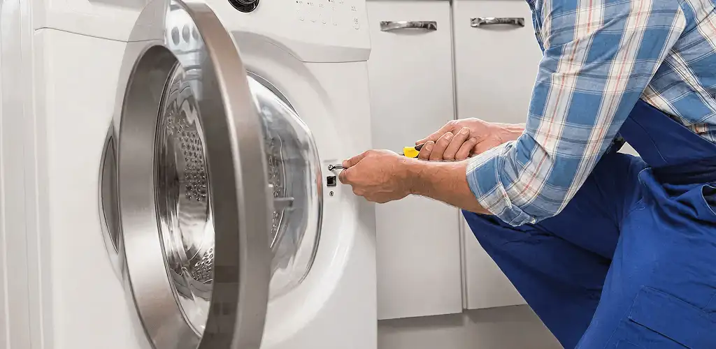Handyman repairing a clothes dryer and checking electrical connections in Tuscaloosa, AL