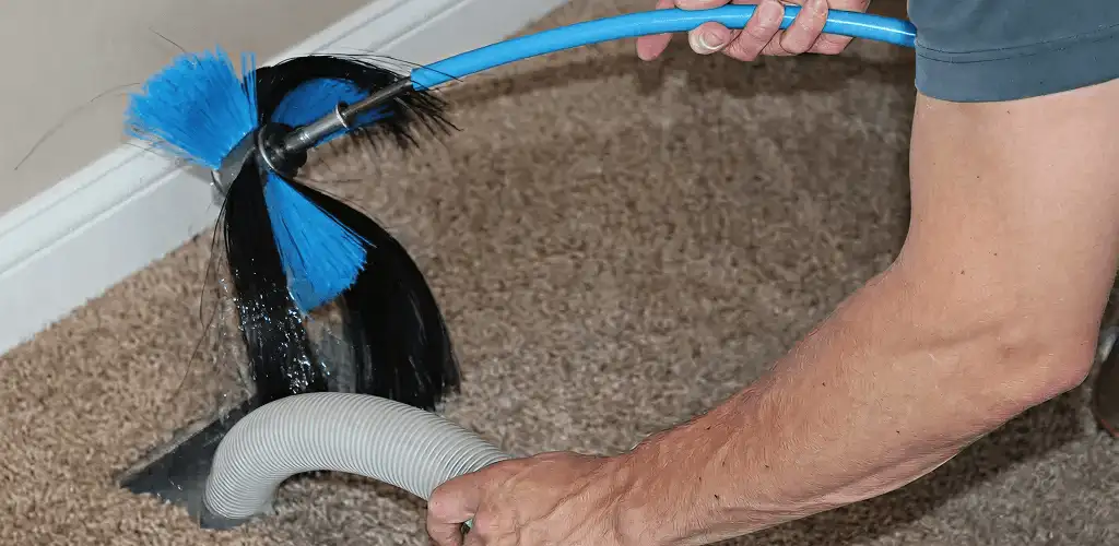 Dryer vent cleaning technician brushing lint from a vent line in Tuscaloosa, AL