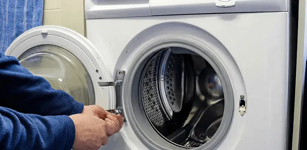 Washing machine repair handyman checking a front-load washer door and latch in Tuscaloosa, AL