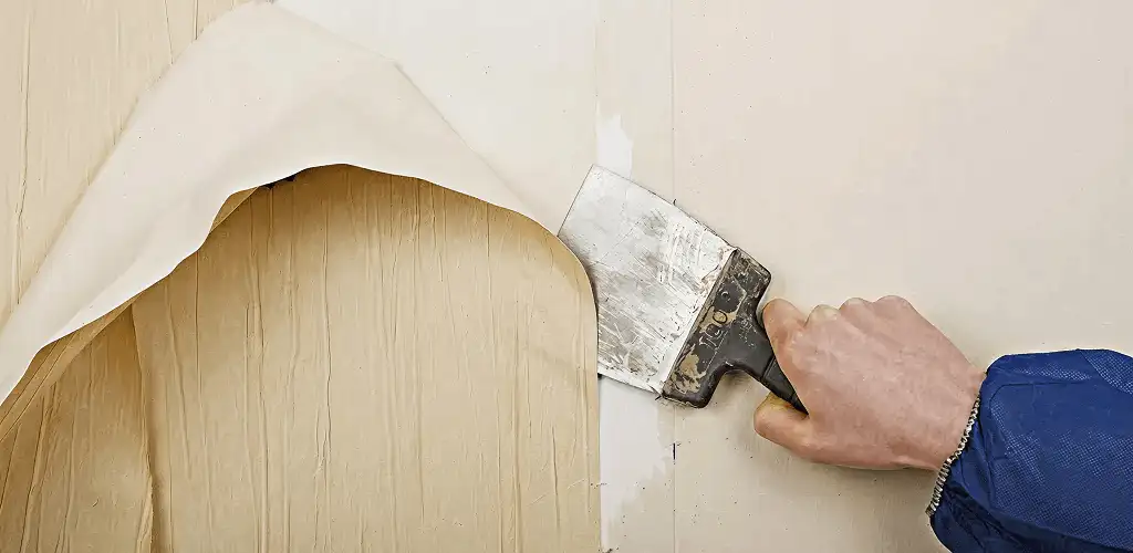 Handyman removing wallpaper with a scraper for wall preparation in Tuscaloosa, AL