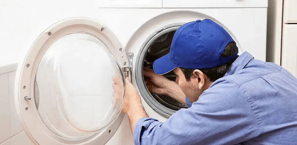 Washing machine repair handyman inspecting a front-load washer drum in Tuscaloosa, AL