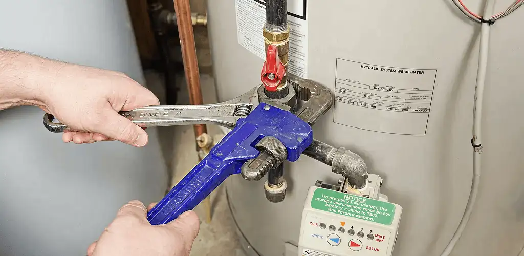 Water heater repair technician tightening the shutoff valve and supply line in Tuscaloosa, AL